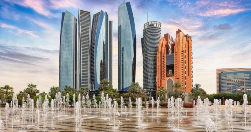 The skyscrapers of Abu Dhabi at dusk with bubbling fountains in the foreground.