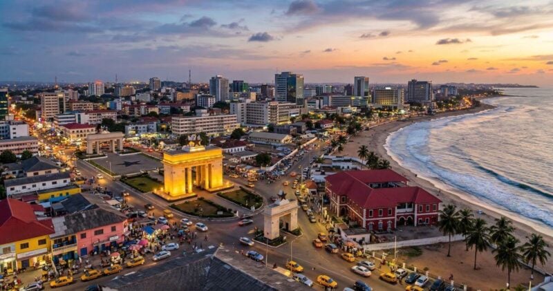 Ghana flight deal: Elevated view of Accra skyline and the Independence Arch near the Atlantic coast.